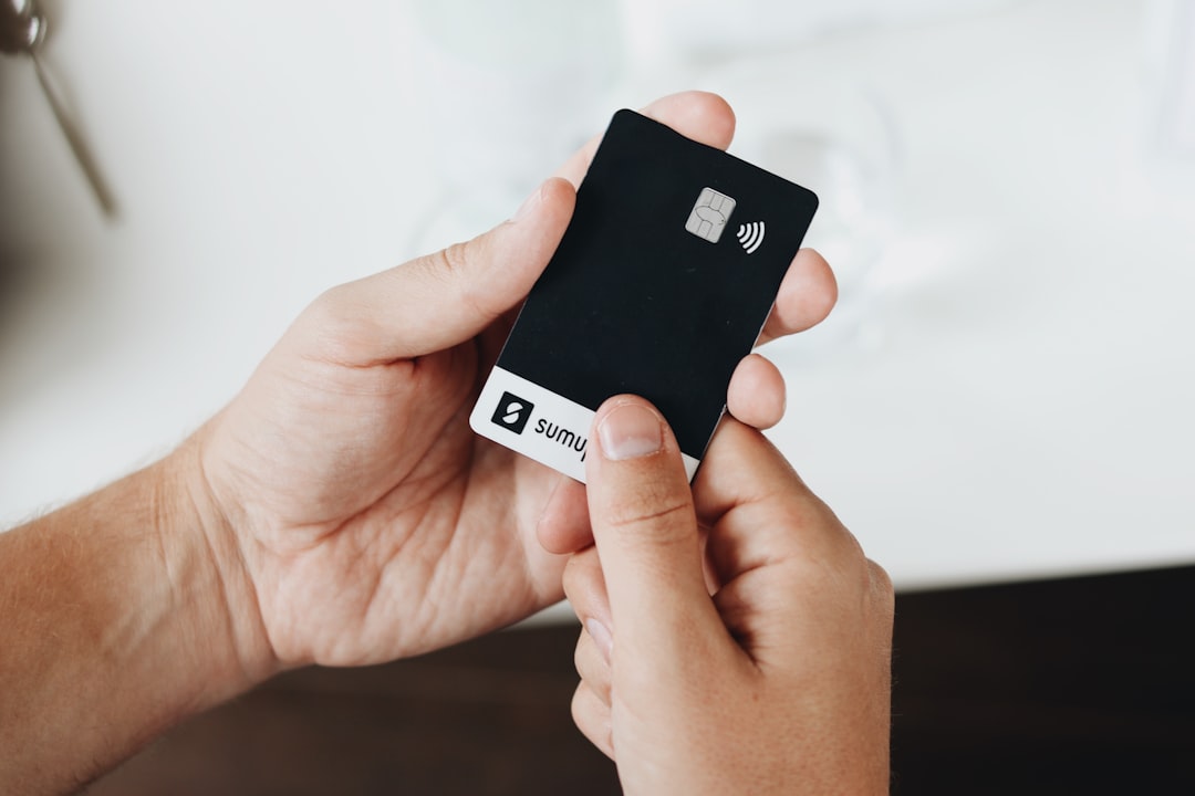 A hand holding a sleek black SumUp card, showcasing the ease of using the card for contactless payments.